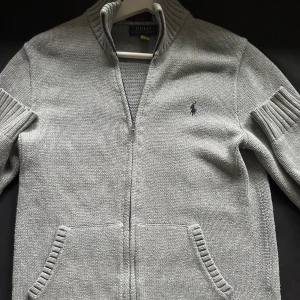 Grå stickad tröja  Ralph Lauren - Säljer en snygg och bekväm grå stickad tröja från Polo Ralph Lauren, är i storlek 14 men som en xs, passar dig bäst som är kring 175cm lång! köpt för 1499kr och säljes för 699kr. Är i toppskick och är där med inga defekter! skriv gärna vid intresse😊