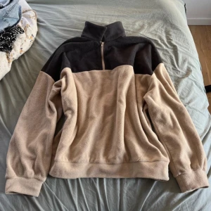 Beige och svart fleece tröja - Säljer en supermysig beige och mörkbrun fleece tröja. Den har en dragkedja vid halsen och långa ärmar. Perfekt för kalla dagar och att mysa i hemma. Tröjan är i bra skick och väldigt bekväm att ha på sig. Passar snyggt overzised på mig som har S/M!