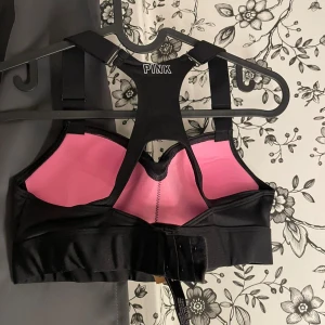 Svart sport-bh från PINK - Säljer en svart sport-bh från PINK med rosa insida. Den har en racerback-design och justerbara axelband för bästa passform. Perfekt för träning eller vardagsbruk.