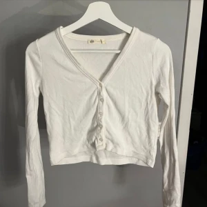 Kofta - Kort ribbad kofta med knappar. Sitter åt det tajtare hållet. Superfin att ha både öppen och stängd