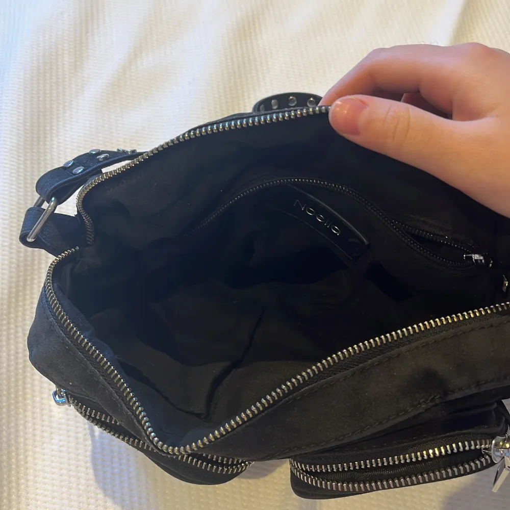 Säljer min fina svarta noella väska, älskar väskan men den kommer inte längre till användning. Den stora dragkedjan är sönder men rälsen är hel så den ska kunna lagas utan att behöva byta ut den därför säljer jag den så billigt🫶🏻. Väskor.