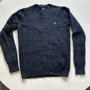 Kabelstickad Gant tröja  - Går aldrig ur tiden. Kanelstickad bomullströja  med rundhals ( ny pris 1400kr) snygg i färg och form fortfarande. 