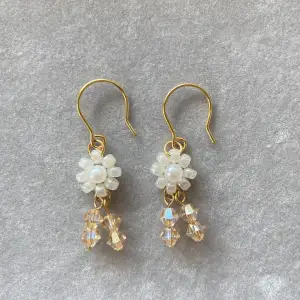 Hemgorda örhängen med blomma design och vackra crystal pärlor. Material: glas pärlor och pläterade gulda öronkrokar.