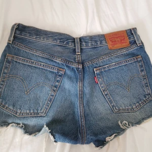 Levi's jeansshorts 501 W26 - Korta Levi's jeansshorts, high waist, modell 501, perfekt till sommaren! "slitaget" fanns där när jag köpte dvs en del av modellen! Passar XS/S 