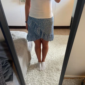 Blå kjol - Säljer en fin blå blommig kjol från SHEIN, säljer den då jag har en liknande. Dragkedjan är trasig högst upp men är inget som syns. Jag kommer tyvärr inte ihåg vad jag köpte den för men den kommer säljas för 25kr, skriv om ni har några frågor!