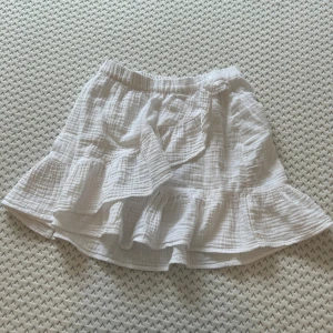 Vit kjol från Gina Tricot - En vit kjol från Gina Tricot med elastisk midja och volangdetaljer. Kjolen har en kort längd och är tillverkad i ett lätt och luftigt material. Den är i bra skick 🩷Säljer för 70 kr❤️