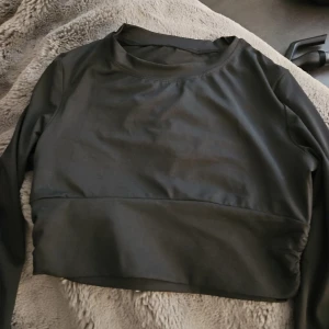 Träningstopp nytt - Svart långärmad träningstopp med rund halsringning. Tröjan är något kortare i modellen och har vid ärmslutet hål för tummarna . Katt finns I hemmet