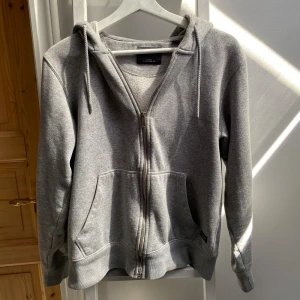 Zip hoodie, grå. - En grå zip hoodie från Jack & Jones. Är för liten för mig. Bra skick och använd då och då.