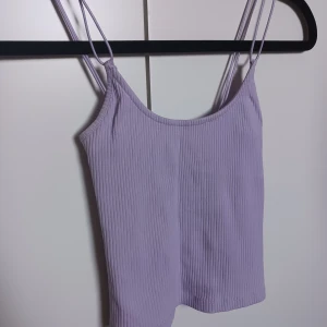 Lila croptop - Lila ribbad croptop med dubbla axelband. Supersöt och passar till allt. Har inte längre användning för den och därför säljer jag.  Köparen står för frakt 💕