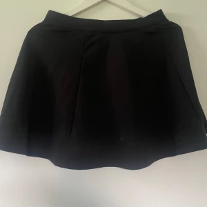 Svart kjol - En helt vanlig svart ”tennis kjol”. Den är alltså inte tajt utan faller fint på höften. Sparsamt använd!