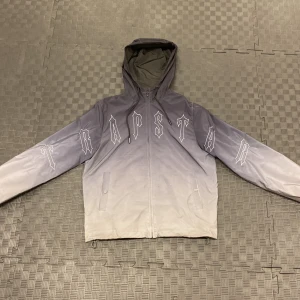 Trapstar Windbreaker - Ljus-mörk grå trapstar vind jacka som har används i några månader. Skicket är 8/10 för att knappen på fickan är sönder. Köpt från Uk.trapstarlondon.com för 2400, Priset kan diskuteras!