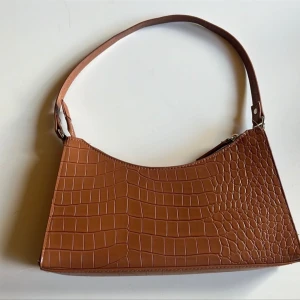 Brun väska - Liten brun väska från Bik Bok med litet innerfack. Använts ett fåtal gånger så den är i fint skick.