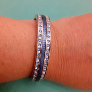 Armring - Armring, 18 cm, silverfärgad metall med blåa stenar och ett blått band mellan. 
