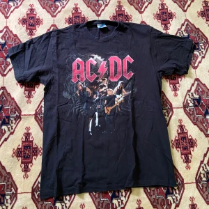 ACDC tshirt - En acdc tshirt. Storlek L. 55cm öppning längsner. Krage till ner 70 cm (längd). Armhåla till armhåla 52 cm. Krage till ärm 36 cm