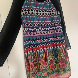 Klänning Desigual - Klänning Desigual med transparent tyg över armarna och bak och en underklänning.  Dragkedja bak.  Stl 44 men känns som en 38-40