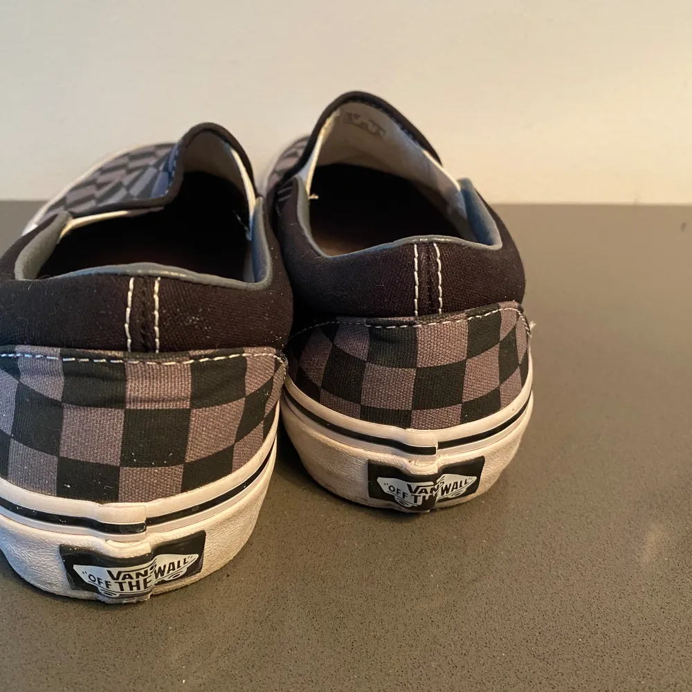 Grå och svarta Vans slip on sneaker i strl 37.  Endast använda 2-3 gånger och ser i princip nya ut förutom några grå/svarta märken på kanten på sulan.. Skor.