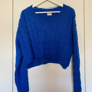 Blå stickad tröja - Blå stickad tröja med v-ringning. Något croppad modell. Storlek S