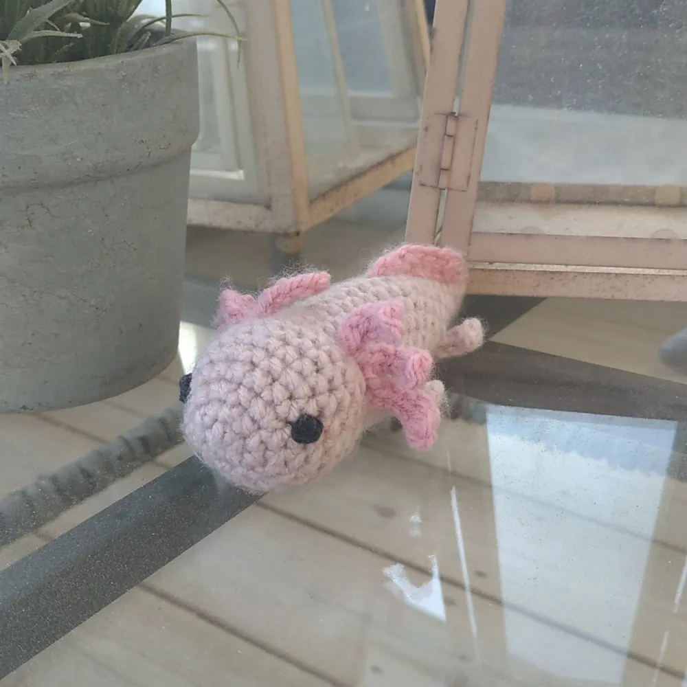 En fin rosa liten virkad axolotl. Handgjord av mig. Vill du ha den i en annan färg (t.ex grå & svart) så får du skicka ett DM på instagram så löser jag det åt dig! Går att köpa via instagram också, finns länkad i bion @ SmyckEmma heter jag där. . Övrigt.
