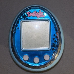 Tamagotchi  - Tamagotchi köpt 2014 på BR-leksaker. Finns ögla för att hänga i ett snöre eller liknade. Vet inte om den fungerar då jag inte får upp skruven till batteriet. Sista bilden för storleksreferens💕