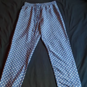 Mjuka byxor med blå mönster - Dehär supermysiga byxorna har tunt silkesliknande tyg och vit och blå mönstring. Pefekta som mysbyxor eller till sommaren! Resor i midjan och längst ner på benen. Har fickor! Står att det är L men skulle säga att de funkar för alla mellan S och L:)