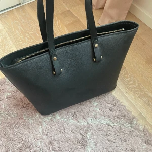Väska - Jag säljer en svart väska från hm som jag inte använder längre. Väskan kan man använda till allt, plus den är väldigt rymlig. Köp för 300kr. Priset kan diskuteras vid snabbt köp
