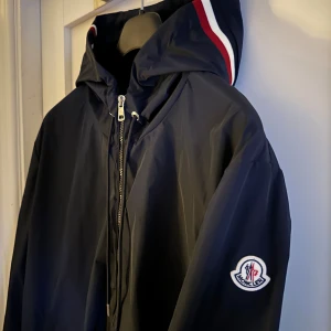 Moncler windbreaker - En riktigt stilren och funktionell windbreaker från moncler i marinblå. Den är använd 1 gång och är i nyskick.  Storlek 5 men passar Large. Nfc