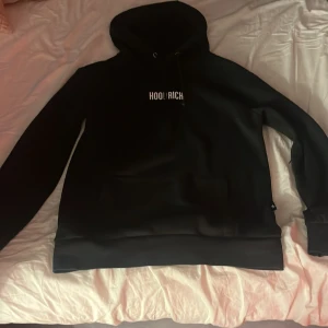 Hoodrich hoodie svart - Hoodien är i bra skick men insidan är inte lika mjuk/fluffig som ny. Har för mig att den är köpt på man så funkar för både män och kvinnor. Snörena är även lite förstörda långt ned.