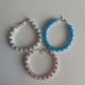 Egengjorda armband - Tre egengjorda pärlarmband i färgerna rosa, blå och vit alla med silver accenter. 