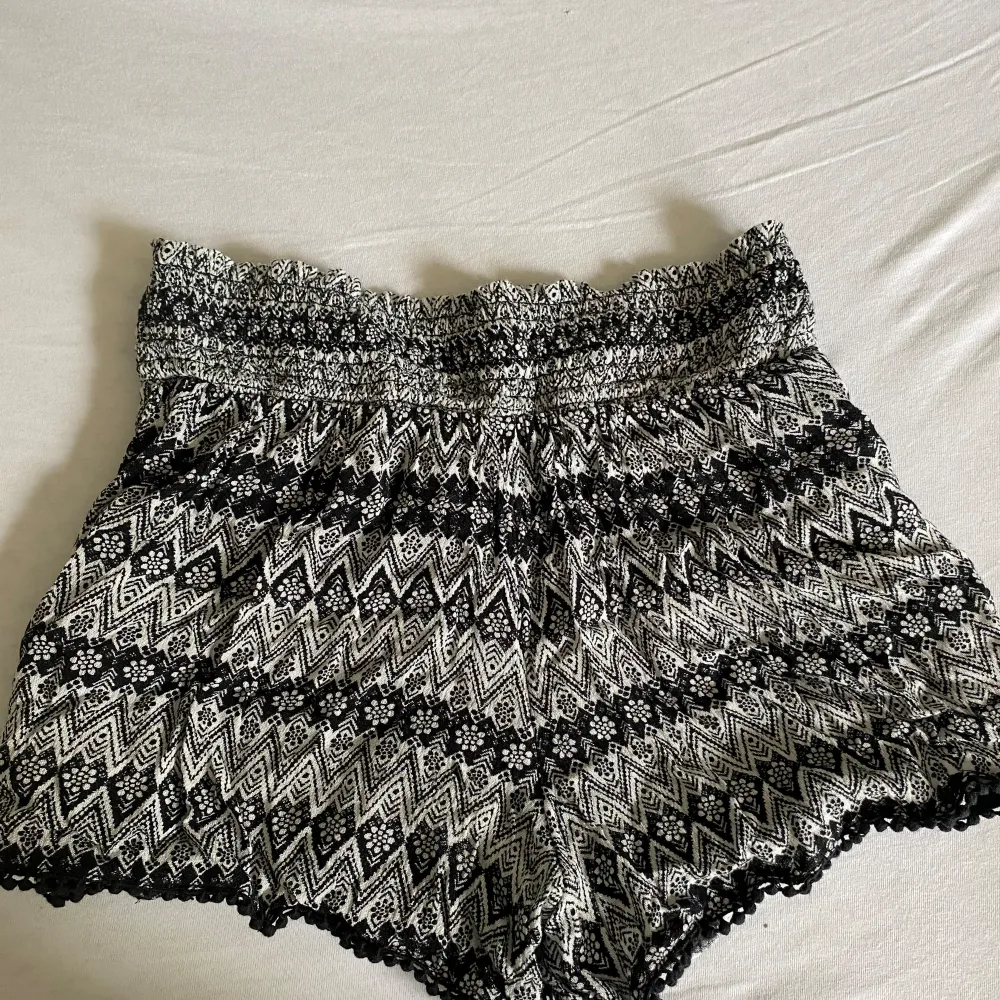 Ett par svartvita shorts från KappAhl med med ett zigzag-mönster. Shortsen har en elastisk midja och spetsdetaljer vid kanterna. Sparsamt använda, därmed bra skick. . Shorts.