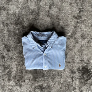 Ralph lauren skjorta - Säljer min superfina Ralph lauren skjorta i storlek M.  Passar S/M. Den är ljusblå vit randig och har noll defekter. Perfekt för sommarn😊mått i bild så ni kan kolla hemma o se om den passar. 