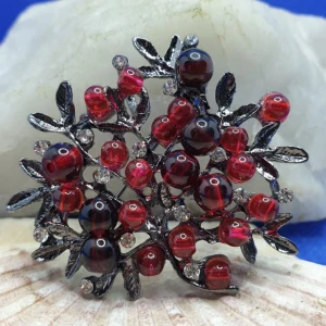 Brosch / Hänge - Vacker Blomma med Röda riktiga stenar - Den här broschen föreställer en växt och måtten är ca 5× 4.5cm. Antiksilverfärgad metall med bl.a transparanta kristaller samt riktiga ädel/halvädelstenar.