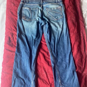 Blå jeansbyxor - Ett par blå jeansbyxor med slitna detaljer och fickor både fram och bak. Byxorna har en normal passform och är i vanligt jeansmaterial