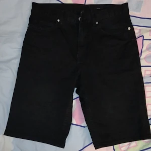 Långa jeanshorts - Svarta unisex jeansshorts som slutar ovanför knäskålen, i mycket bra skick! Riktiga fickor bak och fram, silverimiterade knappar och blixtlås. Storlek 29 (rekommenderar om du har xs på byxor och mindre höfter). Kontakta mig vid frågor! ☺️