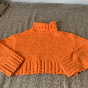 Orange stickad polotröja från H&M Divided - En orange stickad polotröja från H&M Divided. Tröjan har långa ärmar och ribbstickade muddar vid ärmslut, nederkant och krage. Den är i storlek S.