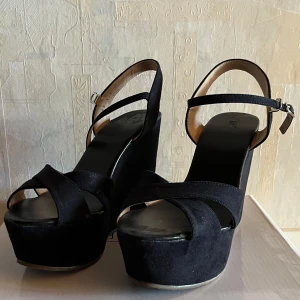 Svarta kilklackar med enkla spännen - Nyskick, endast använt 1 gång. Sköna & stabila skor. Stl 37.