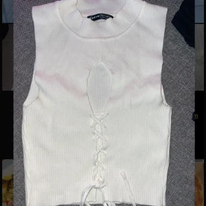 Topp  - En fin vit topp med snörning som man kan knyta fritt hur man vill. Ribbat tyg. Har aldrig använt den och den är i bra kvalitet 