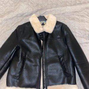 Skinnjacka med krämig päls - Skinnjacka med päls runt nacken och vid armarna. Fickor på båda sidorna. Sitter lite löst även om man har storlek S. 