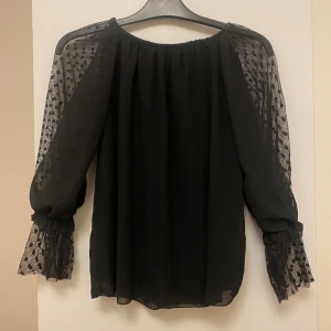 En svart blusa  - Synlig vid armerna, kall och skön 