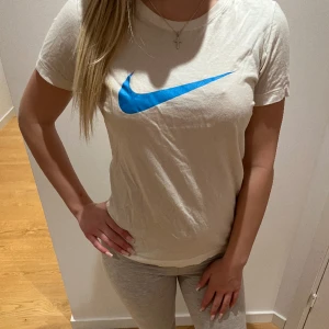 Vit Niketröja - Säljer min vita träningströja från Nike med blått Nike-märke som inte kommer till användning💗sitter supersnyggt, ger fin form. Har oftast storlek Xs i tröjor men skulle säga att denna sitter mer som en storlek S än M.