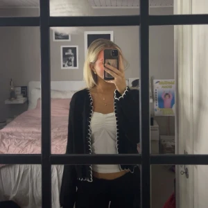 Svart stickad kofta - En svart stickad kofta med vita detaljer och knappar. Den är endast provad och aldrig använd. Köpt på asos och är nu slutsåld. 