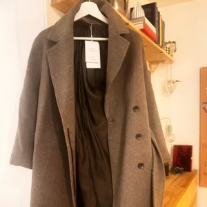 & other stories kappa - En grå kappa från other stories i storlek 32. Inköpt i fjol, men helt oanvänd med etiketter/prislapp kvar. Kappan är helt oanvänd med prislappar/etiketter kvar!  