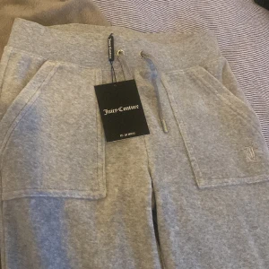 Grå juicy byxor - Helt oanvända gråa juicy byxor med fickor där bak i storlek xs. Prislappen är fortfarande kvar. Säljer p.g.a att det är för långa. Går även med på ett byte för ett par i mindre storlek!💕💕OBS! Frakten är ej inräknad