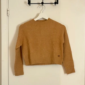 Croppad tröja - Croppad stickad tröja i senapsgul färg. Mjukt och skönt material. 