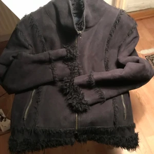 Brooker jacka  - Storlek (?) troligtvis L/XL Jackan är i fint skick. Underbar svart fuskpäls jacka i 100% polyester. Tvättråd: Skontvätt 30C. Två fickor med blixtlås. Blixtlås av metall. 