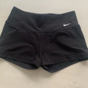 Svarta Nike shorts - Fina nike shorts som ej kommer till användning, inga defekter förutom där bak där storleken och de står men det är ju inget man ser. Utifrån det jättefina och bra längd 