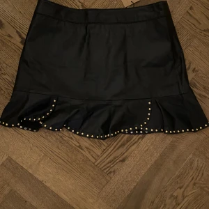 Skinnkjol  - Kjol i 100% äkta läder med guld studs och dragkedja på baksidan. 