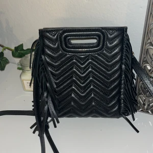 Maje väska  - Säljer denna majeväska som jag köpt här på Plick för ca 2500kr! Den är såklart äkta! Den är knappt använd och ser därför helt ny ut. Man kan även justera bandet för att få önskad längd! Tror jag har kvar dustbag men är osäker på vart. 