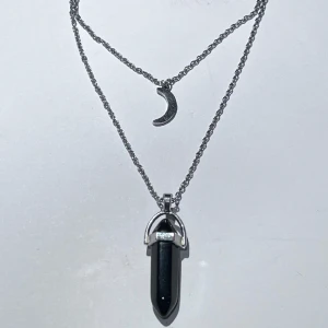 kristall och måne halsband - ett silver halsband med en måne och en låtsas svart kristall ☽ det är två halsband som sitter ihop i ett och är justerbart. använd flertal gånger och är i fint skick, dock lite gråaktigt då det är av låtsas silver. frakt 15kr med swish, eller köp nu!