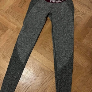 Gymshark Tights  - Gymshark tights. Ljusgrå, med mörkgrå detaljet. Vinrött resår. Använda endast någon gång , jättefina.