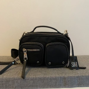 Svart Steve Madden väska - Säljer nu min fina Steve Madden väska då den ej kommer till användning. Köpt på Zalando för 999kr förra sommaren, dock enbart använd enstaka gånger.